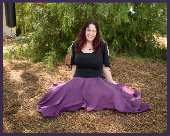 Katie Weatherup sitting on the ground in front of trees. Book a soul retrieval or shamanic healing session with her.